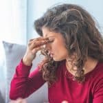 Woman holding the bridge of her nose with her eyes closed from hangover