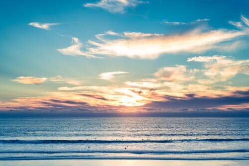 Surfers waiting in Pacific Ocean under a California sunset