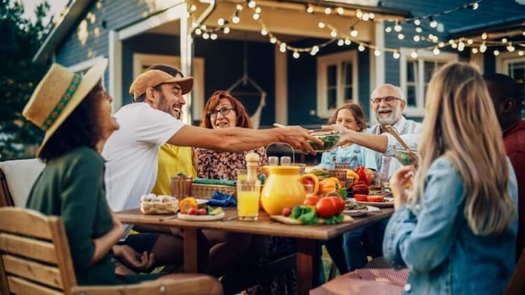 Friends and family smiling around picnic table for bbq