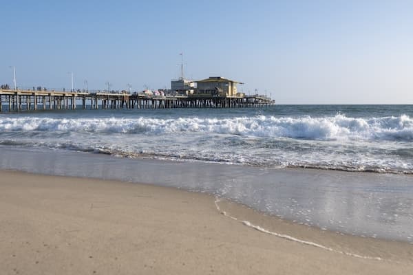 Waves crashing on a sandy beach with pier in background