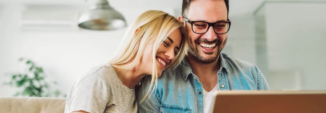 couple smiling looking at a computer
