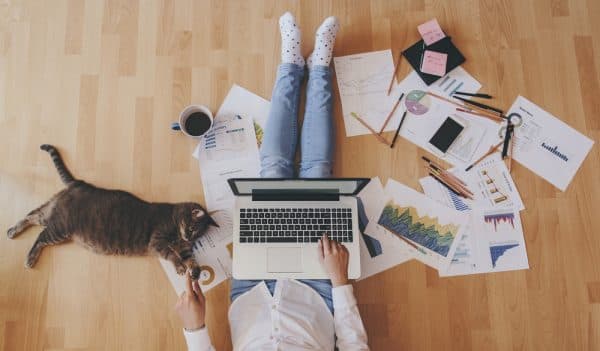person sitting on the floor of their home working on a laptop