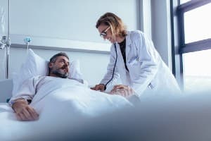 Man in hospital bed with doctor standing over him