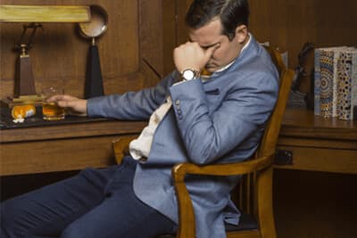 younger man sitting at a desk with alcohol on the table