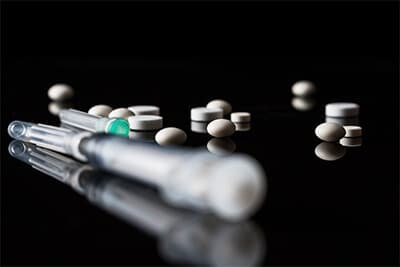 pills and a syringe on a black background
