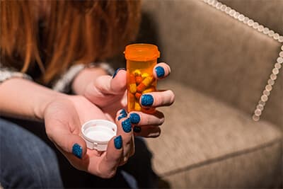 closeup of girls hands holding an open pills bottle with pills in it